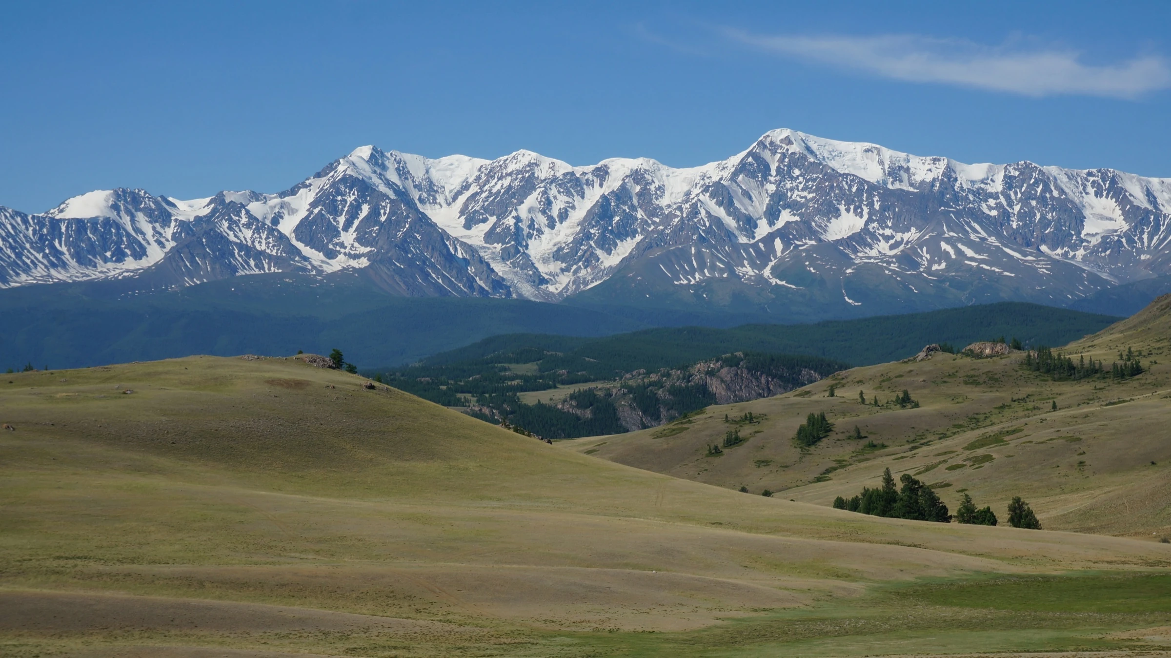 Snow-covered mountain peaks above a green valley