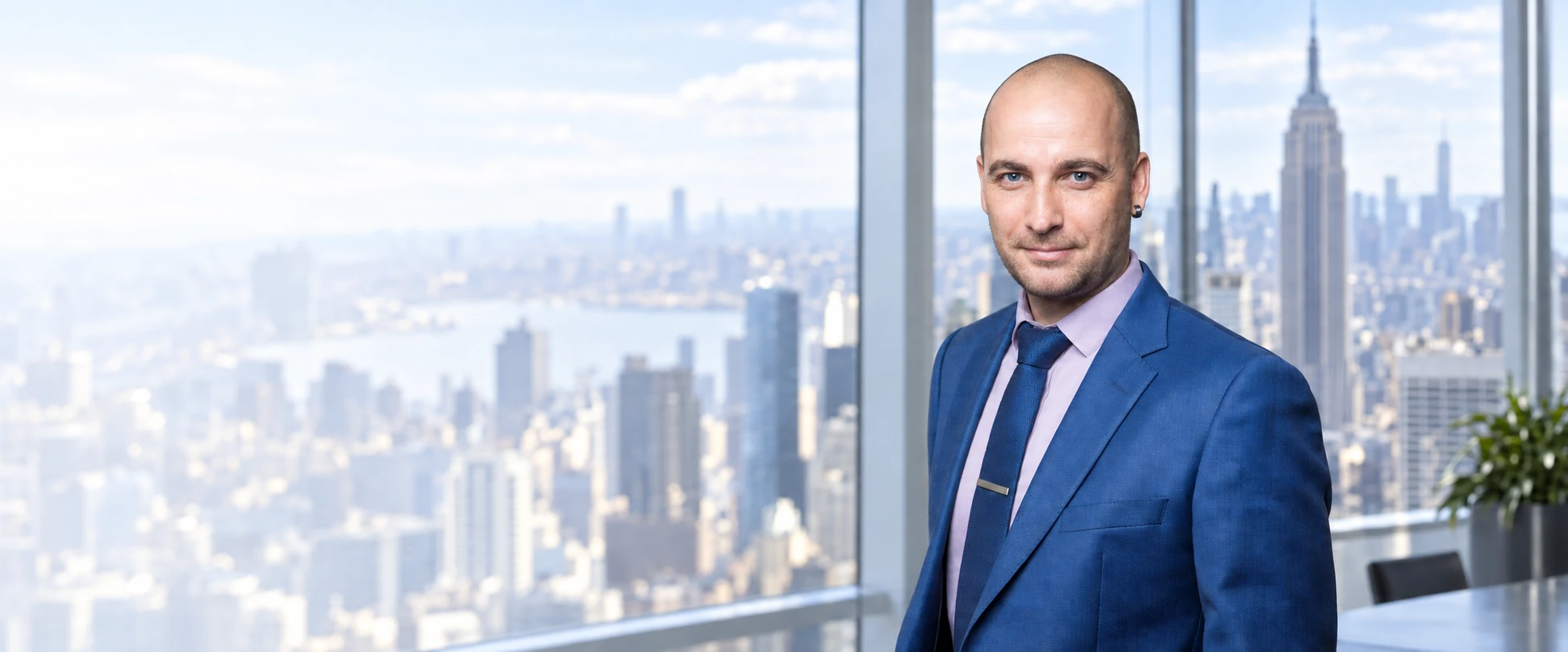 Max Cheprasov in a blue suit with a New York skyline backdrop